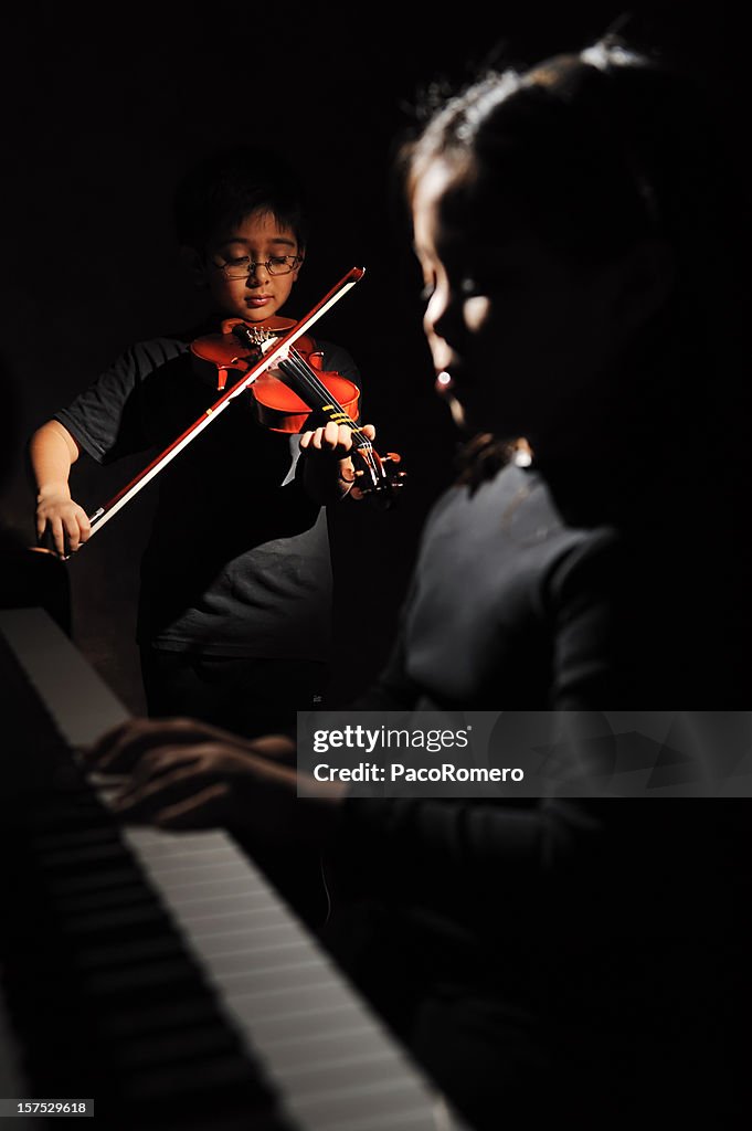 Two children playing piano and violin