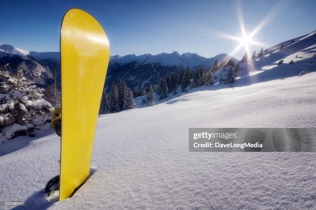 Yellow snowboard in snow on mountain