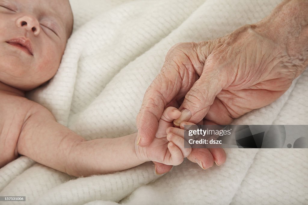 Sleeping baby holding great grandmother's hand