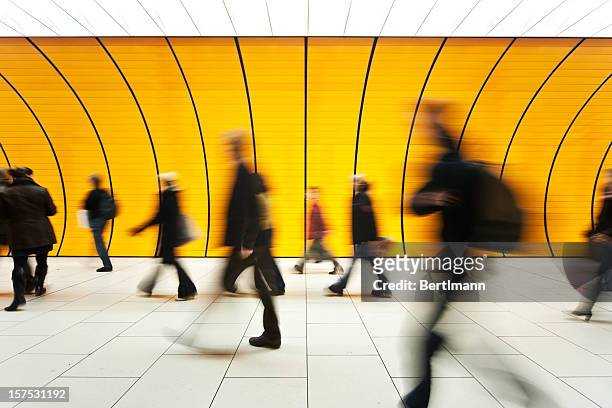 people blurry in motion in yellow tunnel down hallway - city stockfoto's en -beelden