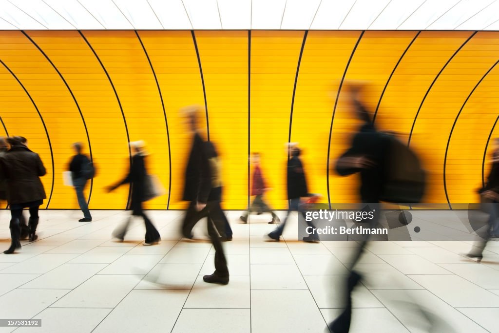 People blurry in motion in yellow tunnel down hallway