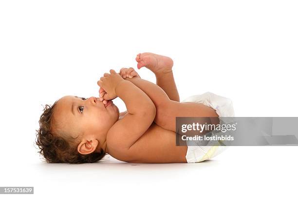 biracial bambino succhiare i suoi piedi isolato su bianco - baby white background foto e immagini stock