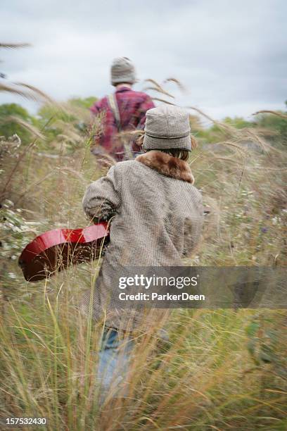 niños caminando a través de hierba con guitars prairie - pata de gallo fotografías e imágenes de stock