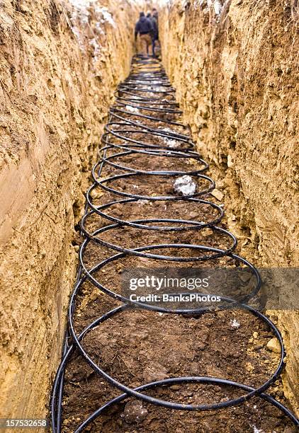 workers laying geothermal coils in an underground trench - geothermische centrale stockfoto's en -beelden