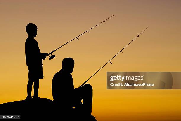 kleine junge und sein großvater angeln bei sonnenuntergang-iv - grandfather silhouette stock-fotos und bilder