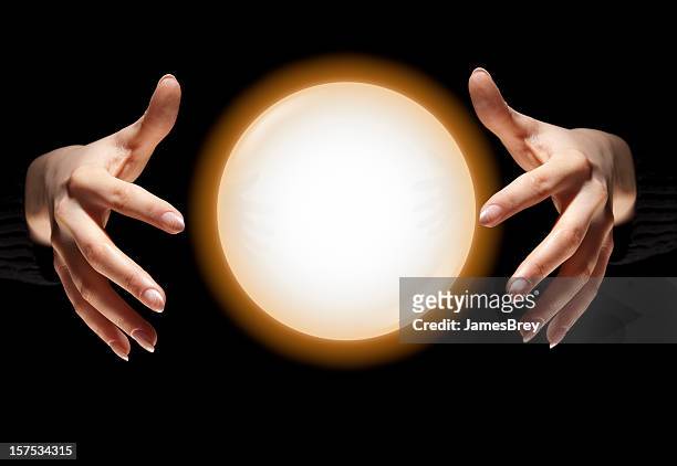 fortune teller's hands with glowing crystal ball, dark black background - fortune teller stock pictures, royalty-free photos & images