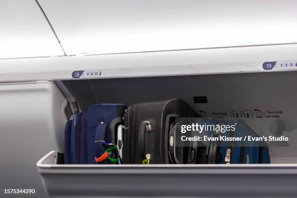 three suitcases in an overhead compartment - equipaje de mano fotografías e imágenes de stock