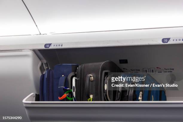 three suitcases in an overhead compartment - evan kissner stock pictures, royalty-free photos & images