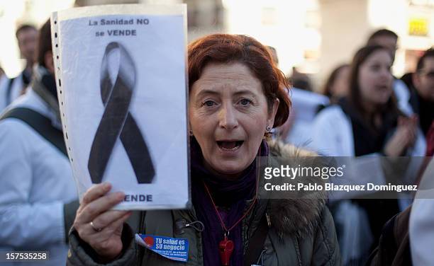 Woman shouts slogan and holds a placard reading 'Health service is not for sale' amid other health workers during a demonstration at Puerta del Sol...