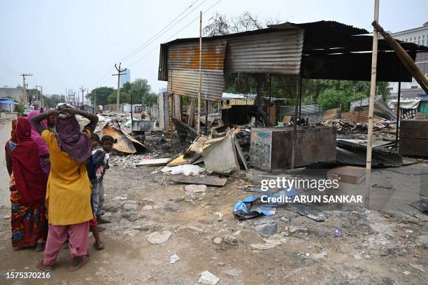 People stand next to a burnt strucutre in Gurugram, Haryana State, on August 4 following sectarian riots. Most mosques were shut for Friday prayers...