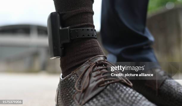 August 2023, Hesse, Weiterstadt: A man wears an electronic residence monitoring device, known as an electronic ankle monitor, for demonstration...