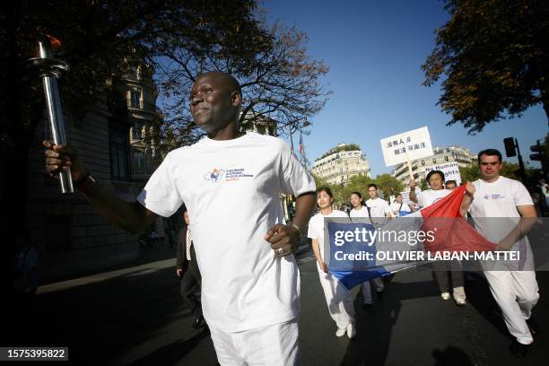 Un homme porte la "flamme des droits de l'Homme", le 16 septembre 2007 dans les rues de Paris, lors d'un rassemblement organisé par la coalition...