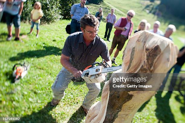 German actor Hans Sigl carves wood with a chainsaw as he visits the filming location of German-Austrian tv serie 'Der Bergdoktor' on September 17,...