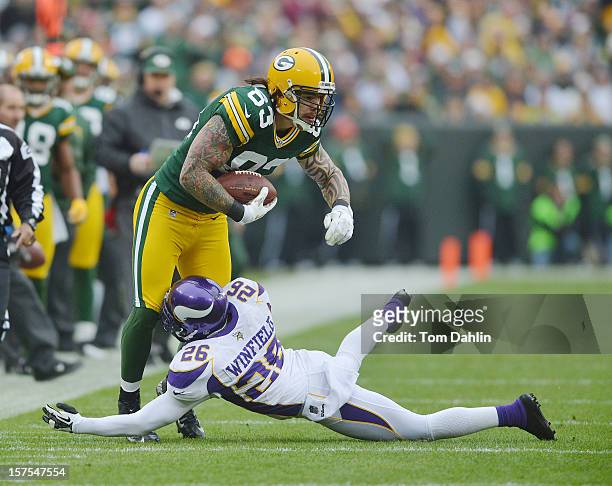Tom Crabtree of the Green Bay Packers carries the ball against Antoine Winfield of the Minnesota Vikings during an NFL game at Lambeau Field on...
