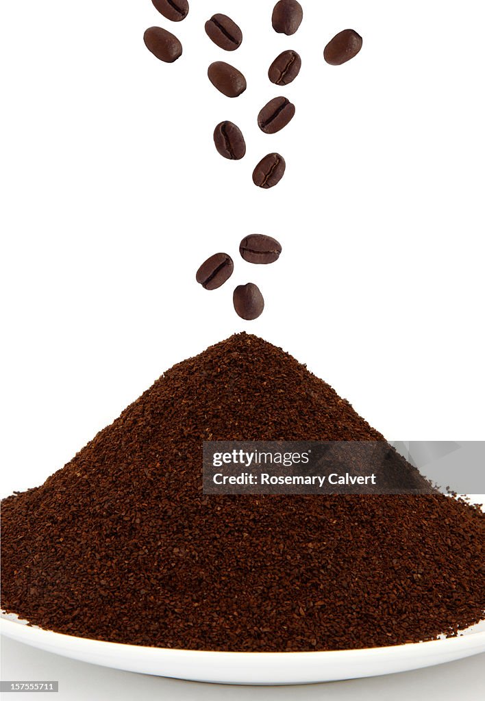 Roasted coffee beans falling onto ground coffee