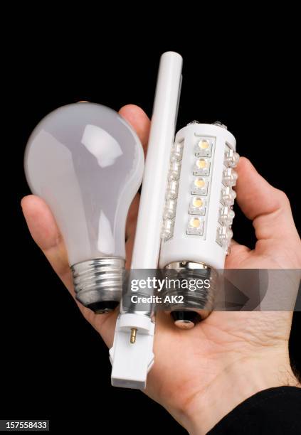 holding various bulbs - fluorescent light bulb stock pictures, royalty-free photos & images