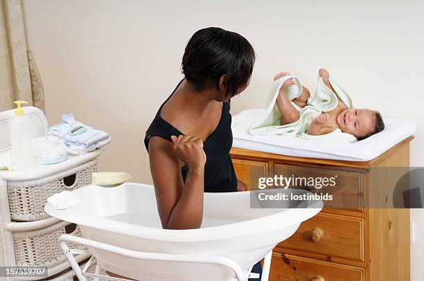 african american woman testing bath water temperature - commode stockfoto's en -beelden