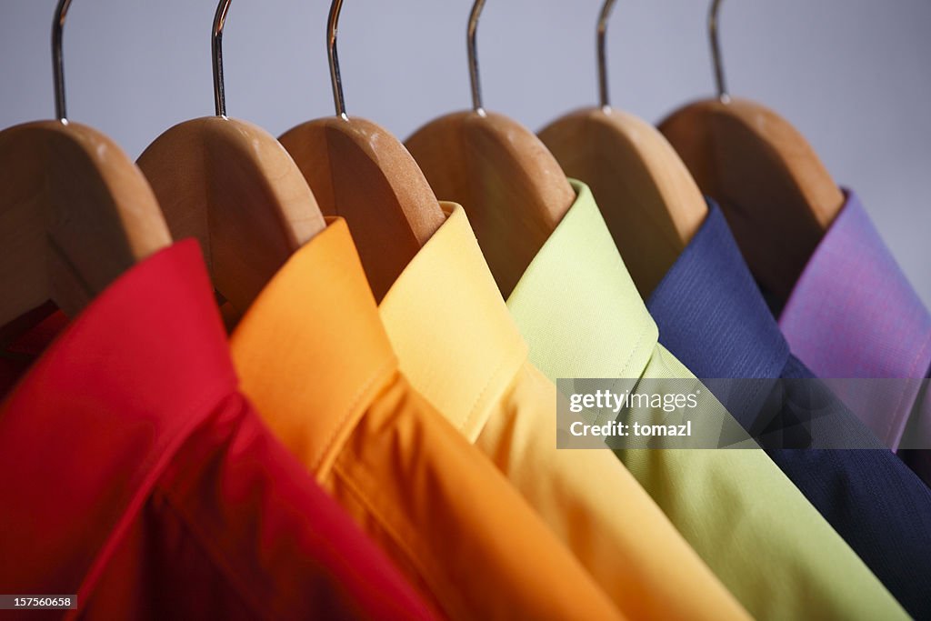 Close-up of rainbow shirt collars hanging in closet