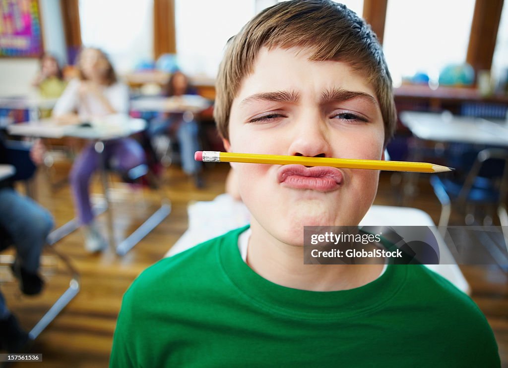 Boy balancing a pencil on his nose at school