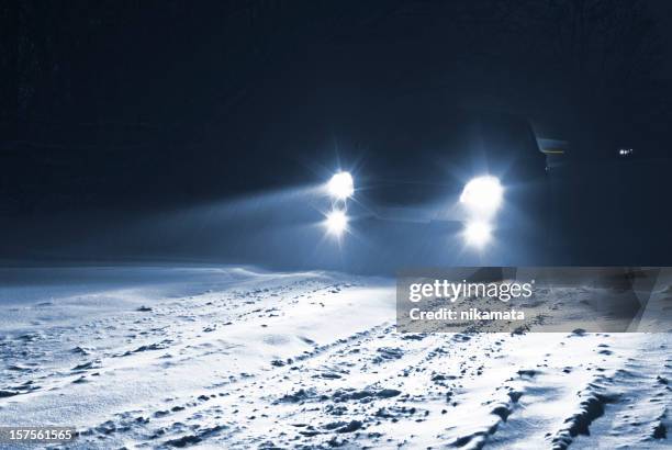 autos fahren auf schnee country road in einem schneesturm. - autoscheinwerfer stock-fotos und bilder