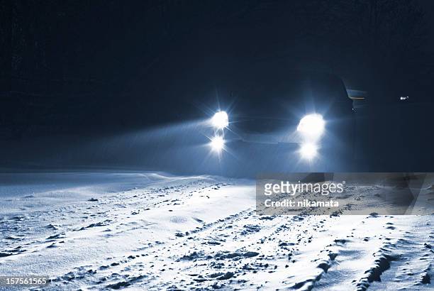 car driving on a snowy country road in a snow storm. - headlamp stock pictures, royalty-free photos & images