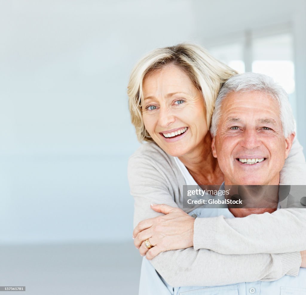 Happy mature lady hugging her husband from behind