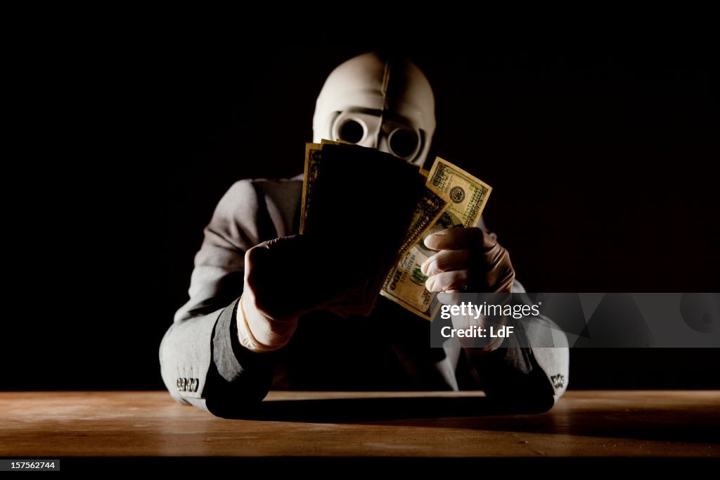 Man counting dollars wearing a gas mask