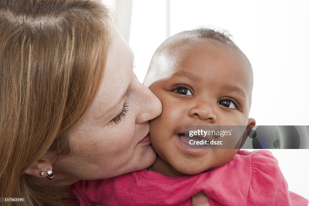 Mother holding adopted baby daughter in mixed race family