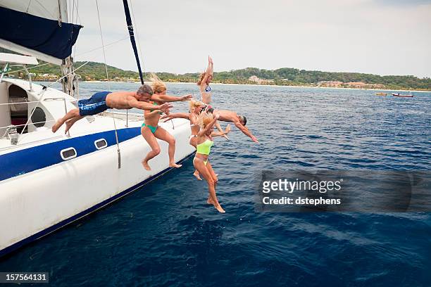 heureux amis sauter sur catamaran dans la mer des caraïbes - catamaran race photos et images de collection