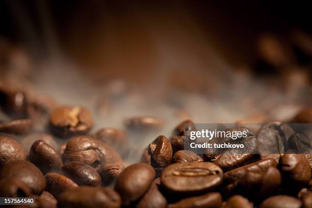 a close-up shot of steamy coffee beans - geroosterd stockfoto's en -beelden