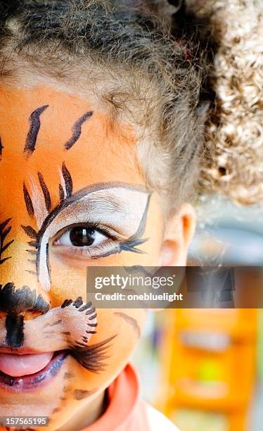 happy child with her tiger face paint. - geschminkt gezicht stockfoto's en -beelden