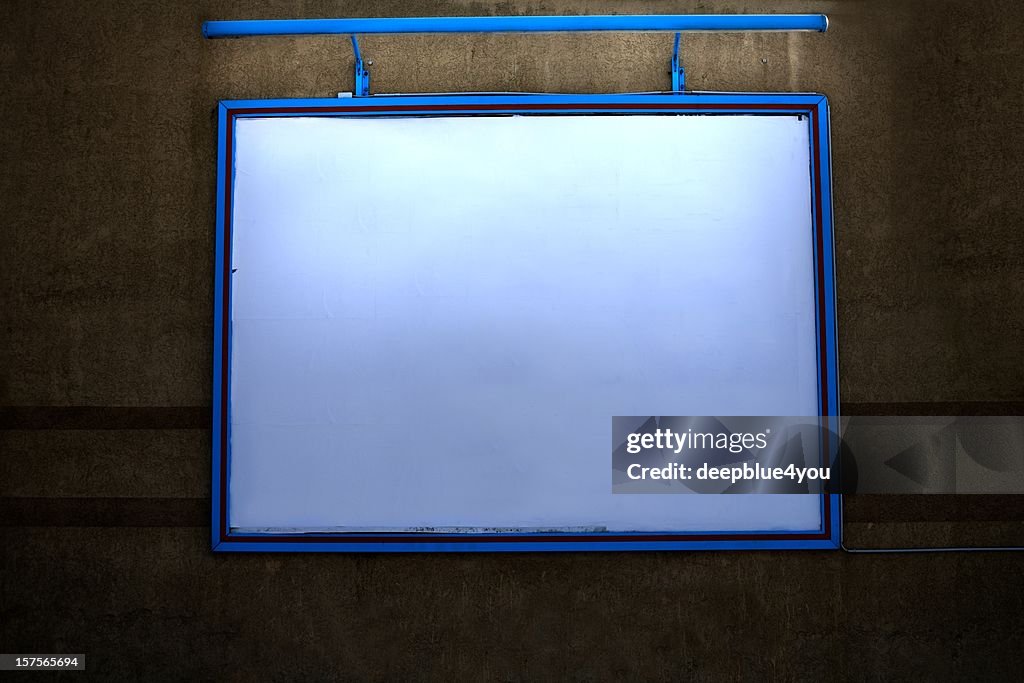 Panneau d'affichage extérieur éclairé avec copyspace sur un mur, de nuit
