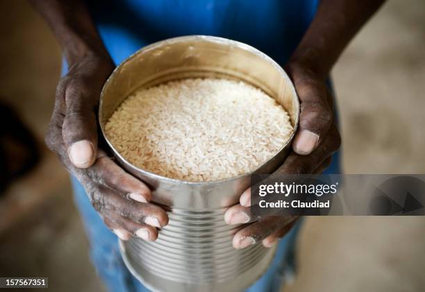 black hands holding can of rice - haiti poverty stock pictures, royalty-free photos & images