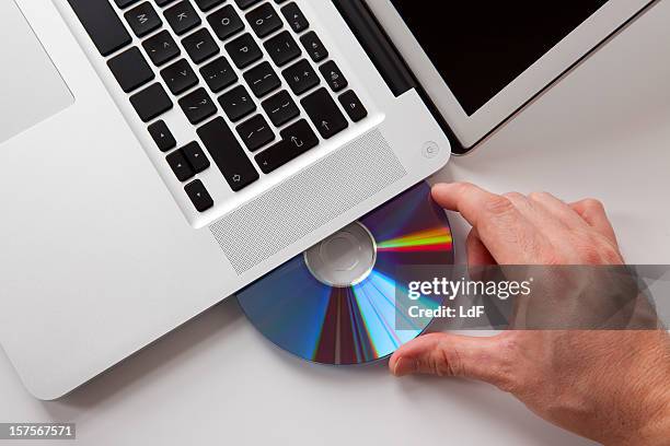 hand inserting a dvd in the laptop - compact disc stock pictures, royalty-free photos & images