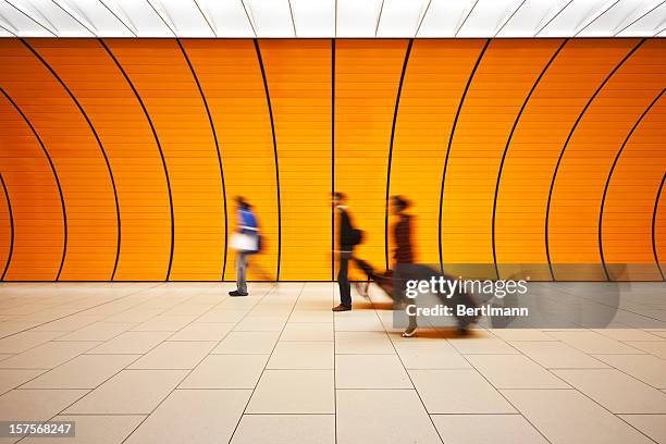 blurred people walking with luggage in an orange tunnel - train arrival stock pictures, royalty-free photos & images