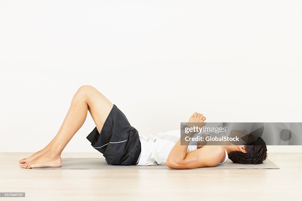 Young man lying on a yoga mat after workout
