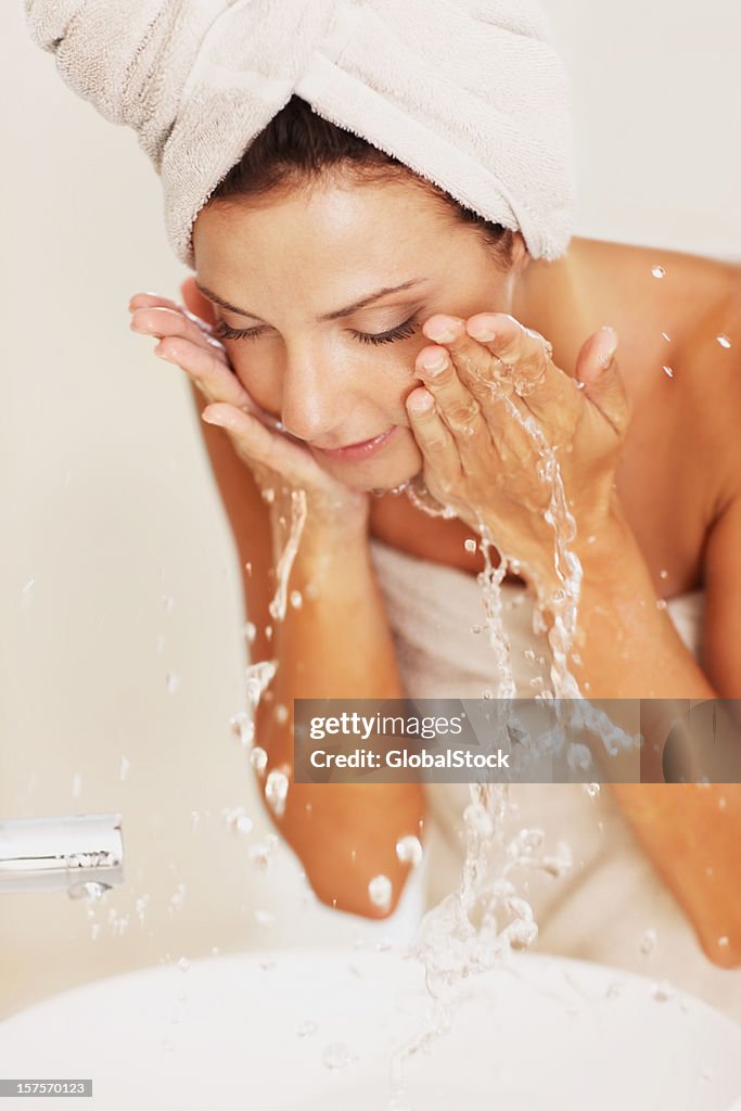 Young woman washing her face with water