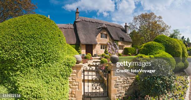 idyllic country cottage thatched roof pretty summer gardens cotswolds uk - huisje stockfoto's en -beelden