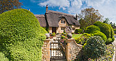 Idyllic country cottage thatched roof pretty summer gardens Cotswolds UK