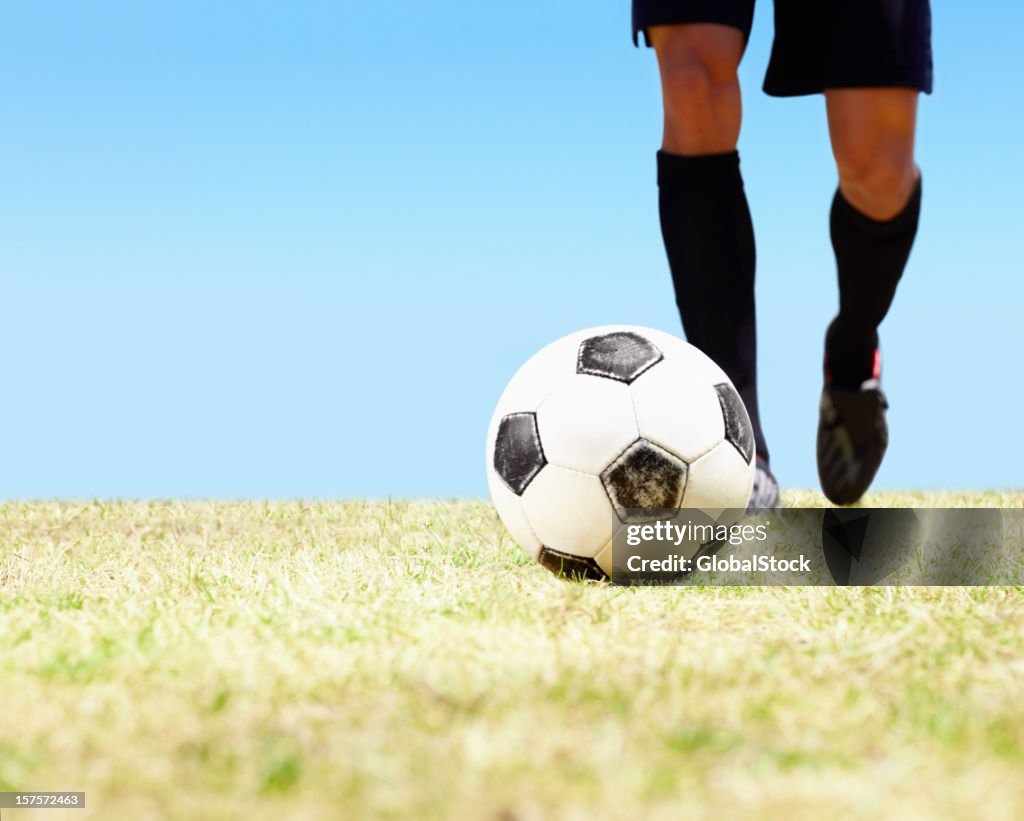 Low section of a footballer ready to kick the ball