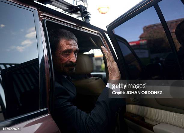 Anti-virus software pioneer John McAfee waves to journalists while leaving, in front of the Supreme Court in Guatemala City on December 04, 2012....
