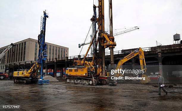 Man on a cell phone walks past a Komatsu Ltd. Excavator before the start of the groundbreaking ceremony for the Hudson Yards development in New York,...