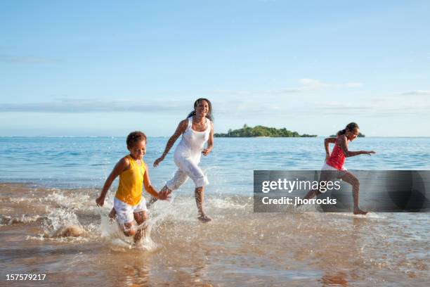 fijian mother and daughters running on beach - melanesia stock pictures, royalty-free photos & images