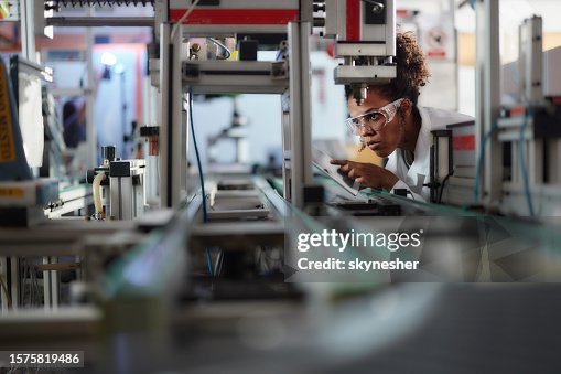 Young black scientist using touchpad while working on machinery in a lab.