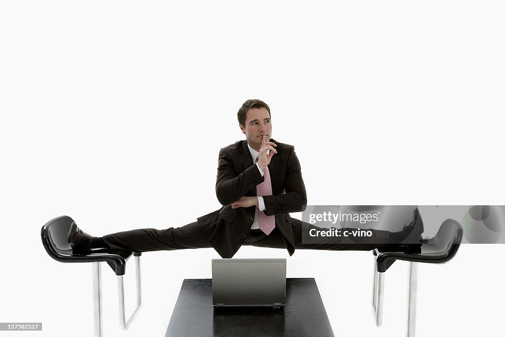 Manager doing a split between two black chairs in a suit