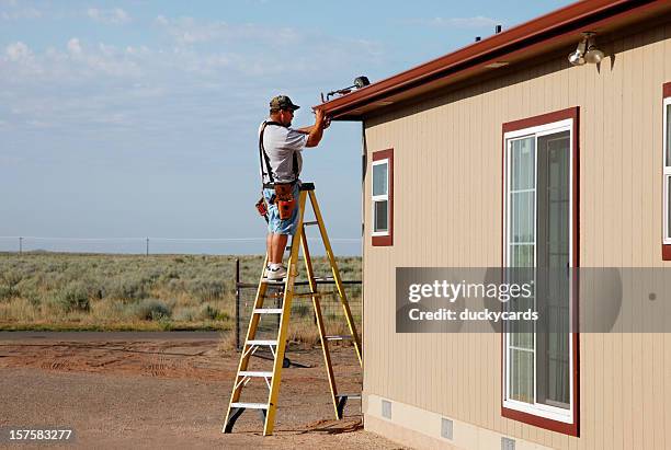 man installing downspout and seamless gutters - dakgoot stockfoto's en -beelden