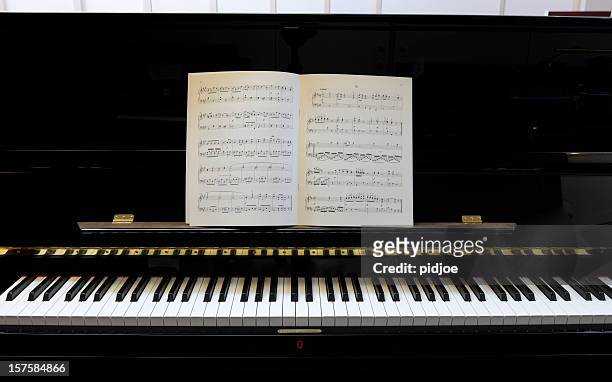sheet music on black lacquered piano xxxl image - sheet music stock pictures, royalty-free photos & images