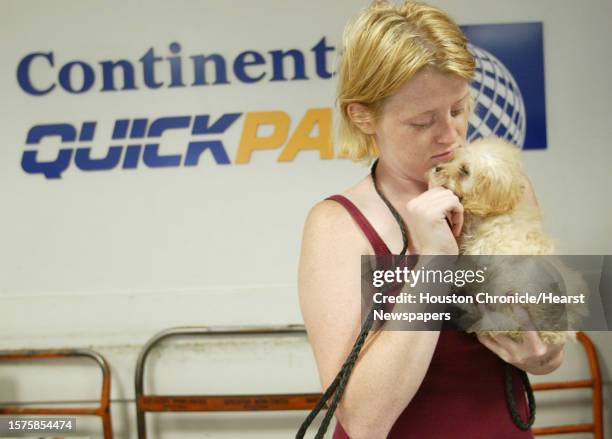 Carrie West, of the Kingwood Pet Camp/Pet on the Go, takes a small puppy out of its cage so it can stretch before it travels through the Continental...