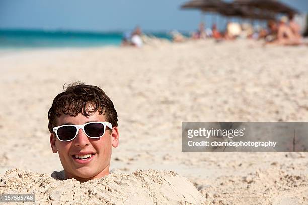 teenage boy enterrada en la arena - enterrado fotografías e imágenes de stock