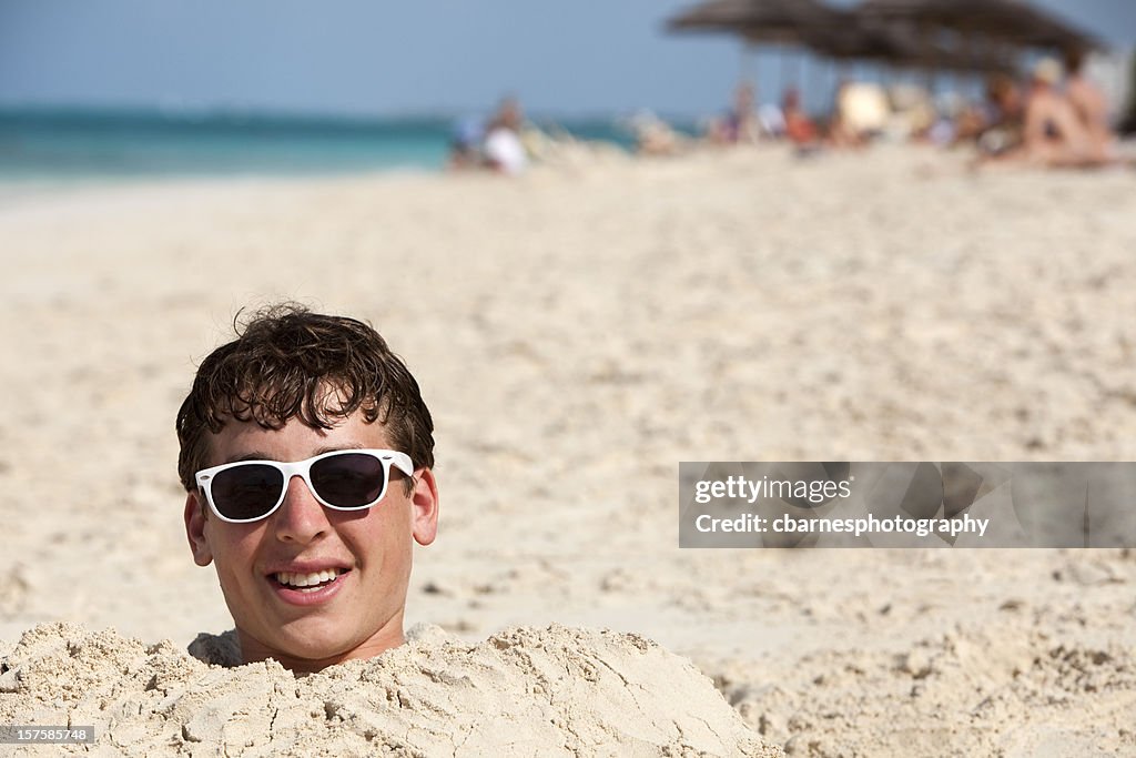 Teenage boy buried in sand